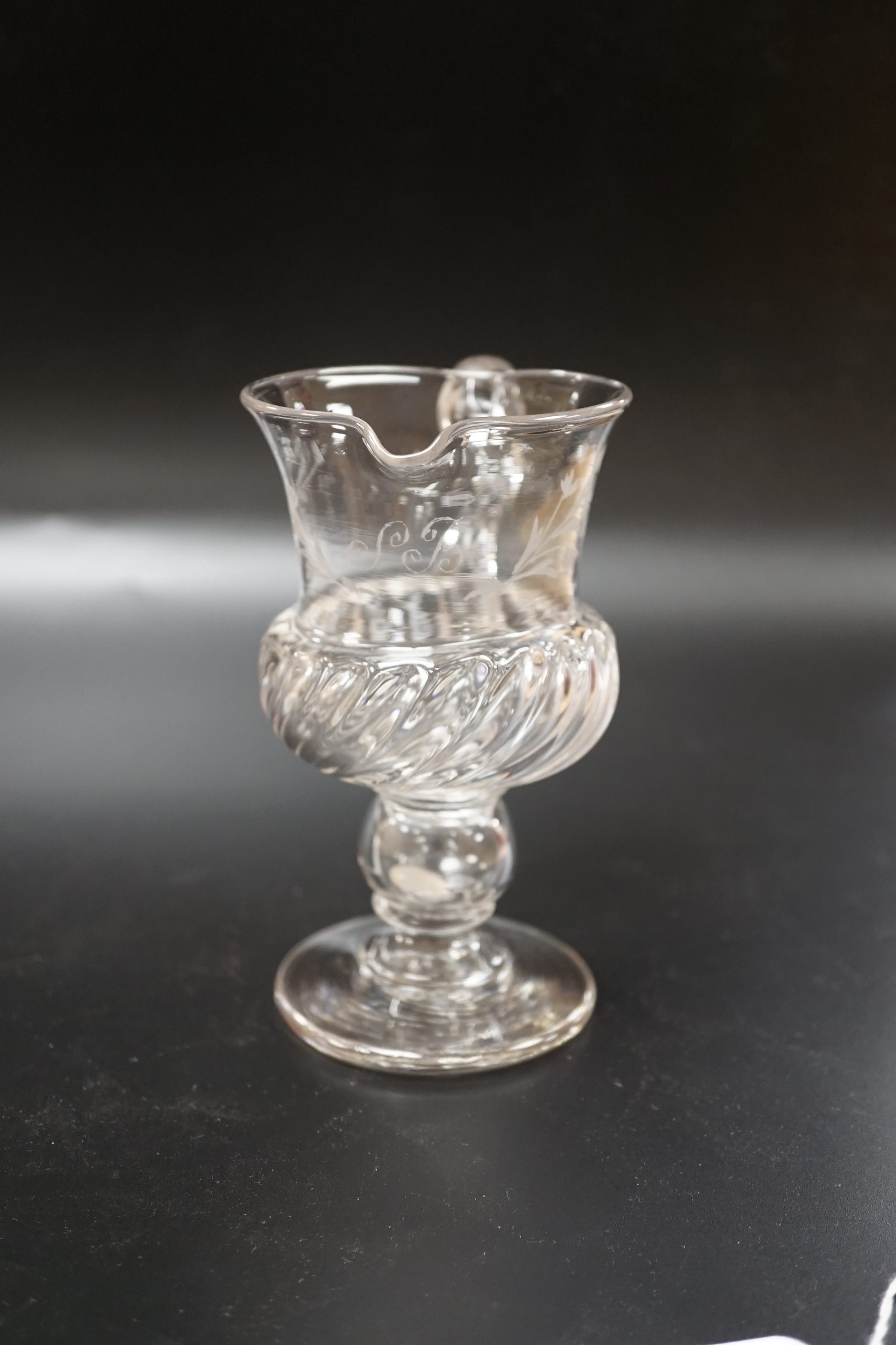 A Georgian glass jug on a stem, knop containing loose Charles II coin and engraved foliage with a central ‘SB’, 13.8cm